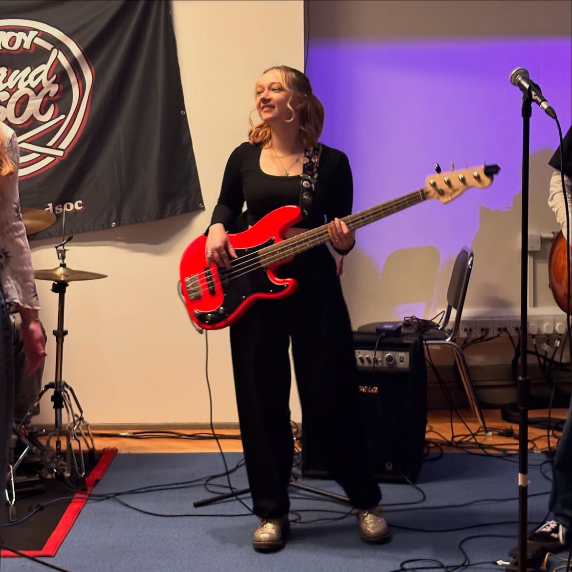 Lottie Victoria smiling while playing bass on stage